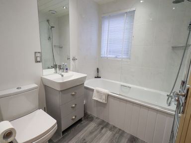 A bathroom with a toilet sink cabinet and bathtub with shower at Cherry Tree Lodge Calgarth 37 White Cross Bay near Windermere