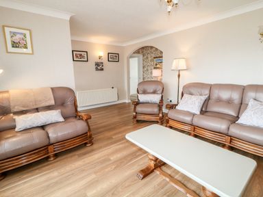 A living room with leather sofas coffee table floor lamp and framed pictures at 27 Pinewood Hill Warrenpoint Northern Ireland