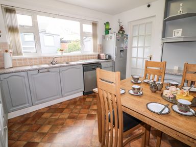 A kitchen with wooden chairs around a dining table set with teacups plates and scones at 27 Pinewood Hill in Warrenpoint Northern Ireland