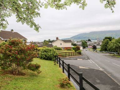A residential street with houses bushes and trees overlooking a town and hills at 27 Pinewood Hill Warrenpoint Northern Ireland