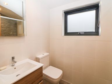 A bathroom with a sink and toilet under a frosted window at Stables Lodge in Wingerworth