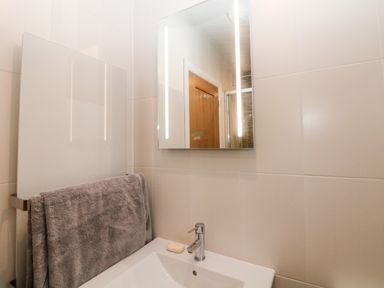 A bathroom sink with a soap bar and a mirror above it and a gray towel hanging on a radiator at Stables Lodge in Wingerworth