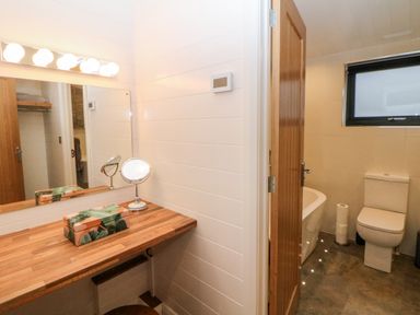 A bathroom with a wooden countertop and mirror and a toilet with a window at Stables Lodge in Wingerworth