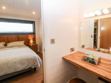 A bedroom with a bed and bedside table next to a dressing table with a mirror and a decorative box at Stables Lodge in Wingerworth