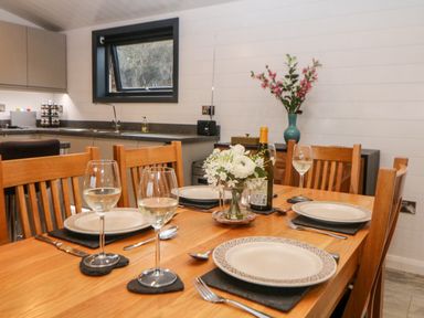 A dining table set with plates glasses cutlery and a flower vase in a kitchen at Stables Lodge in Wingerworth