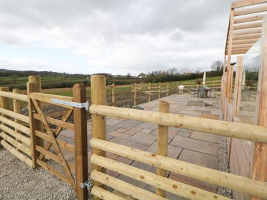 An outdoor patio area with wooden fencing and gate overlooking fields at Stables Lodge in Wingerworth