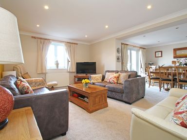 A living room with sofas and a coffee table connected to a dining area with a table and chairs at Wheal Kendall in Mevagissey