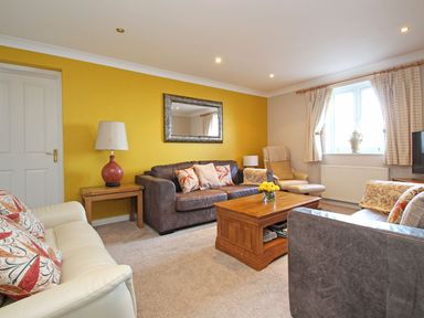 A living room with sofas coffee table lamp and window at Wheal Kendall in Mevagissey
