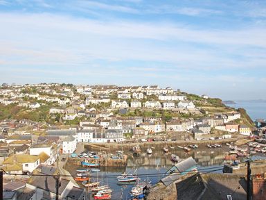 A coastal town with houses on a hillside and boats in a harbor at Wheal Kendall in Mevagissey