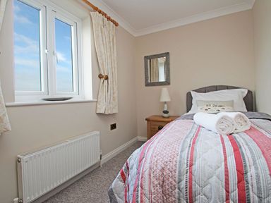 A small bedroom with a single bed bedside table lamp window and radiator at Wheal Kendall in Mevagissey