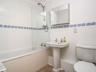 A bathroom with a bathtub shower combination a pedestal sink with taps and a toilet at Wheal Kendall in Mevagissey