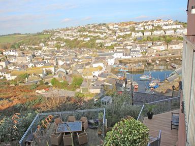 A view over a coastal town with houses boats in the harbor and outdoor furniture on terraces at Wheal Kendall in Mevagissey