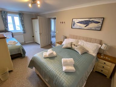 A bedroom with a double bed and a single bed a wardrobe bedside tables and a window at Wheal Kendall in Mevagissey