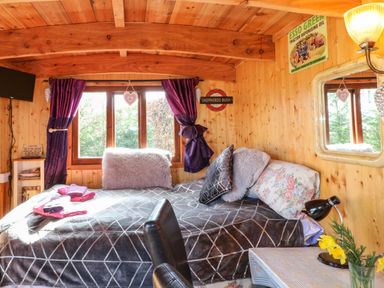 A bedroom with a bed pillow lamp and table with flowers at Packhorse Shepherds Hut in Alderwasley near Wirksworth
