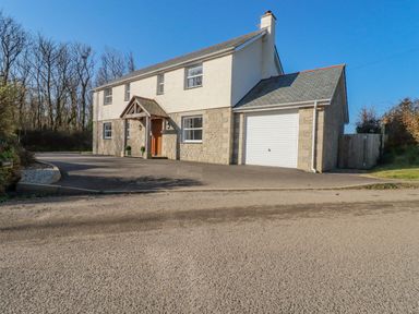 A two story house with a garage and driveway surrounded by trees at Ilgram in St Newlyn East