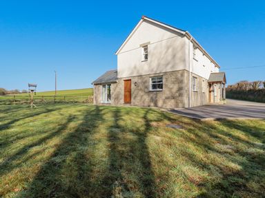 A two story house with a stone and white exterior next to a lawn and a driveway at Ilgram in St Newlyn East
