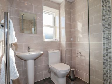 A bathroom with a pedestal sink toilet small mirror window and a towel rail at Ilgram in St Newlyn East