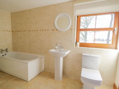 A bathroom with a bathtub a pedestal sink a toilet and a window at Bramblewood Cottage in Crookdake near Bassenthwaite