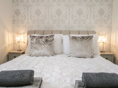 A bedroom with a bed with patterned pillows and folded towels on the bed at Bella Cottage Bolton near Appleby-in-Westmorland