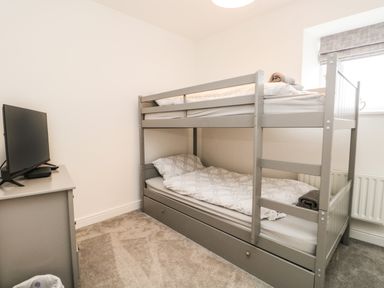 A bedroom with a gray bunk bed and a television on a gray dresser at Bella Cottage Bolton near Appleby-in-Westmorland