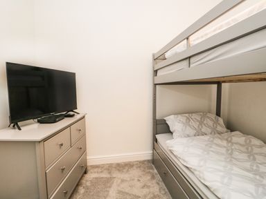 A bedroom with a bunk bed and a dresser with a TV on top at Bella Cottage Bolton near Appleby-in-Westmorland