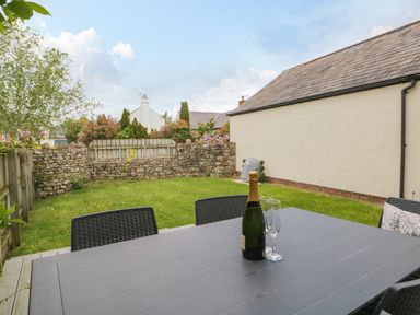 A backyard with a table, chairs, a champagne bottle, and two glasses at Bella Cottage in Bolton near Appleby-in-Westmorland