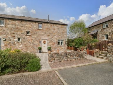 Stone cottages with paved paths fronted by stone walls and shrubbery at Bella Cottage Bolton near Appleby-in-Westmorland