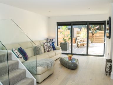A living room with a beige sofa and glass coffee table near sliding glass doors at Sail Loft in Dawlish