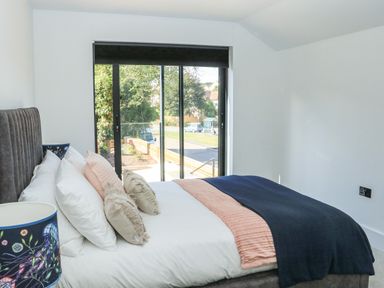 A bedroom with a bed and pillows next to a large window at Sail Loft in Dawlish