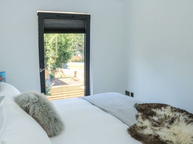 A bedroom with a bed near a window showing an outside garden at Sail Loft in Dawlish