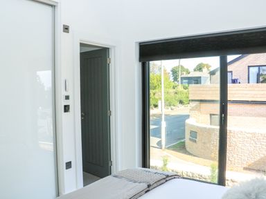 A bedroom with a bed near a large window and an open door in Sail Loft Dawlish