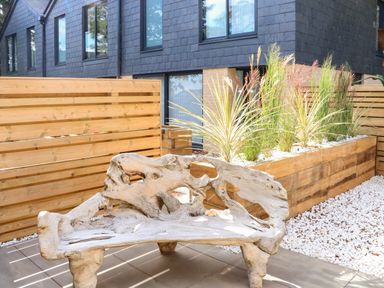 An outdoor area with a wooden bench a wooden fence and a planter with plants at Sail Loft in Dawlish