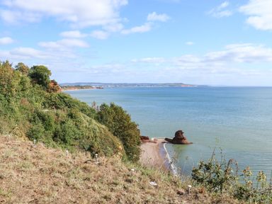 A coastal view with cliffs trees and a rocky beach at Sail Loft in Dawlish