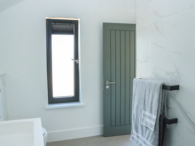 A bathroom with a window a door a towel rack with towels and a sink at Sail Loft in Dawlish