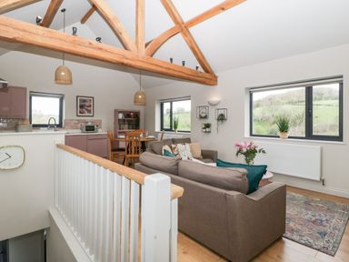 A living room with a brown sofa and a dining table near kitchen cabinets at Sevenwoods View in Longhope