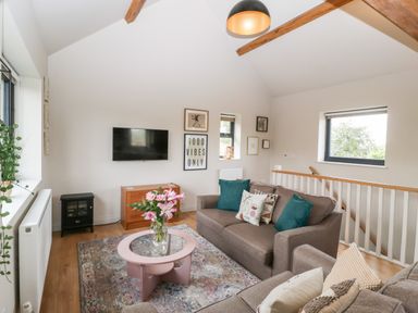 A living room with sofas cushions a coffee table flowers tv and wall art at Sevenwoods View in Longhope