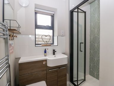 A bathroom with a shower enclosure window and wooden cabinet at Sevenwoods View in Longhope