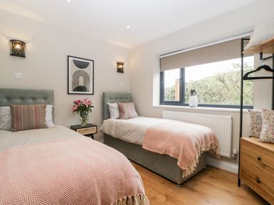 A bedroom with two single beds a window and a small bedside table at Sevenwoods View in Longhope