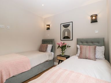A bedroom with two single beds a bedside table with flowers and wall art at Sevenwoods View in Longhope