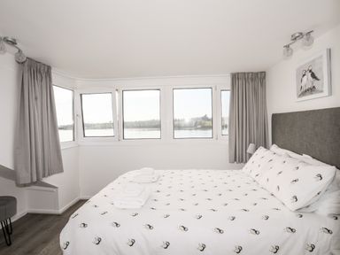 A bedroom with a bed and windows overlooking water at The Summerhouse in Y Felinheli