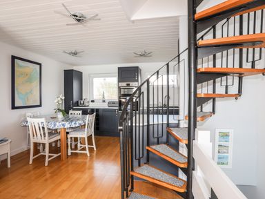A kitchen and dining area with a spiral staircase and a table with chairs at The Summerhouse in Y Felinheli