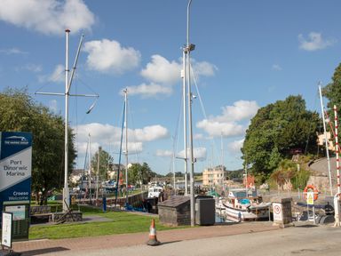 A marina with boats docked along the water and trees in the background at Port Dinorwic Marina