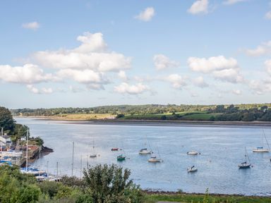 A river with boats anchored near the shore and green fields in the background at The Summerhouse in Y Felinheli
