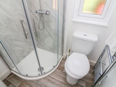 A bathroom with a glass shower enclosure a toilet a window and a heated towel rail at Eden Lodge - Sherwood 21 South Lakeland Leisure Village