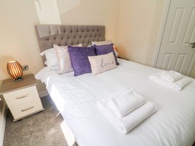 A bedroom with a double bed pillows towels nightstand and a door at Eden Lodge - Sherwood 21 in South Lakeland Leisure Village