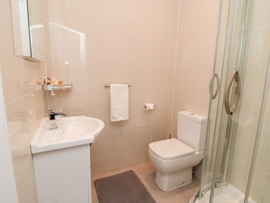 A bathroom with a sink, toilet, towel rack, and glass shower enclosure at Sunset View in Whitby