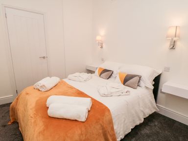 A bedroom with a bed covered in white and orange linens and towels on top at Sunset View in Whitby