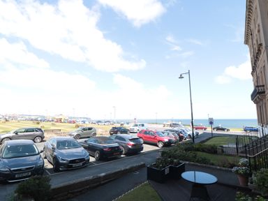 A parking lot by the sea with cars and a building on the right at Sunset View in Whitby