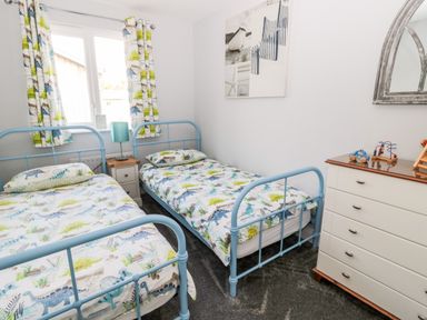 A bedroom with two single beds with dinosaur bedding a chest of drawers and a window with dinosaur curtains at Sea View Lodge Eastfield Hall near Warkworth