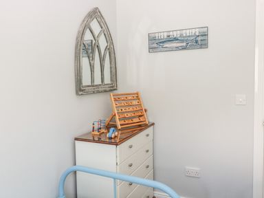 A corner of a room with a white chest of drawers topped with wooden toys a mirror on the wall and a fish and chips sign at Sea View Lodge Eastfield Hall near Warkworth